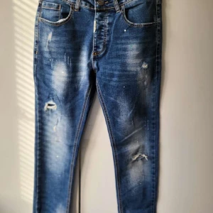  Alessandro Zavetti jeans blåa - Snygga blå jeans från Alessandro Zavetti med slitna detaljer och en cool tvättad look. De har en knappgylf och klassiska fem fickor. Perfekta för en avslappnad stil.