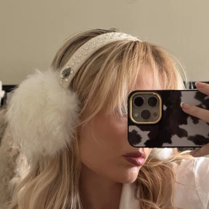 Vita öronmuffar med pärlor och päls från Kurt Geiger - Snygga och varma öronmuffar från Kurt Geiger med vit fluffig päls och ett diadem dekorerat med pärlor. Perfekt för att hålla värmen med stil under kalla dagar.