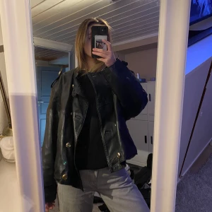 Svart oversized skinnjacka med knappar - Snygg svart skinnjacka med stora knappar och en cool, oversized passform. Jag har stolek s i dem flesta jackor så jackan sitter oversized på mig 