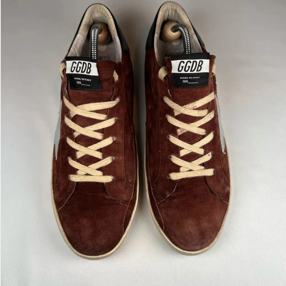 Snygga bruna sneakers i mocka från GGDB med en ikonisk vit stjärna på sidan. Skorna har en rund tå och beige snörning. Den svarta detaljen vid hälen ger en extra touch. Perfekta för en stilren look. Kommer såklart med lådan! Passar 41. Kengät.