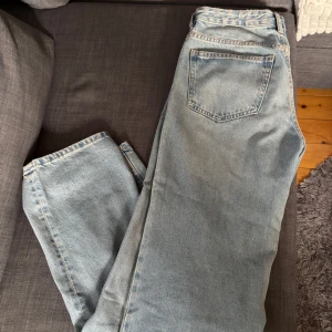 Ljusblå jeansbyxor - Säljer ett par klassiska ljusblå jeans med femficksdesign. Byxorna har en rak passform. De har en knappgylf och är tillverkade i ett slitstarkt denimtyg.