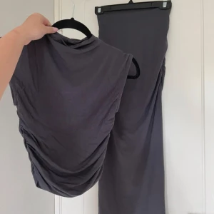 Mörkgrå kjol och topp från Gina Tricot - Snygg mörkgrå kjol och topp från Gina Tricot med draperade detaljer. Perfekt för en stilren look. Settet har en smickrande passform och är tillverkad i ett mjukt material. Toppen är i storlek xs och kjolen i xss. Men passar mig som bär xs/s. Nypris 550kr. 