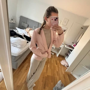 Ljusrosa kavaj - Säljer en stilren ljusrosa kavaj med normal passform. Kavajen har långa ärmar och en klassisk krage. Perfekt för en chic look.