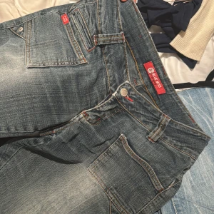 Lågmidjade vintage jeans  - Säljer dessa så snygga vintage jeans med jättecola och unika fickor framtill och så fina bakfickor med blommor på. De är från blue miss i size 25💕Slitna nertill vilket jag såklart kan skicka bild på priv om ni ber mig💗