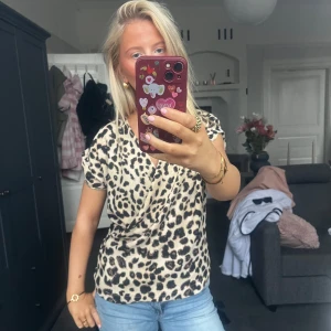 Leopardmönstrad topp - Snygg leopardmönstrad topp med korta ärmar. Perfekt för en trendig look. Toppen har en bekväm passform och är lätt att matcha med jeans eller kjol.