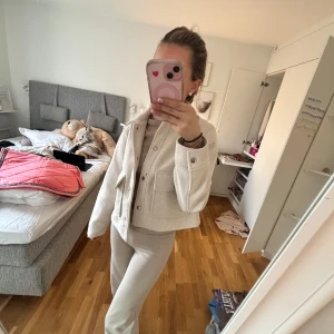 Beige vårjacka med fickor - Säljer en stilren beige vårjacka med knappar och stora fickor framtill. Jackan har en normal passform och är perfekt för lager-på-lager-stil. Den är långärmad och gjord i ett mjukt material som ger en avslappnad look.