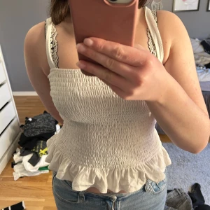 Vitt linne - Söt smockad linnetopp med volangdetalj i nederkant. Storlek L men passar mig som vanligtvis har S.