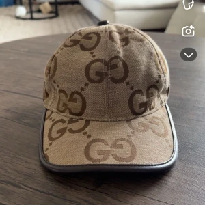 Beige keps med GG-mönster - Snygg beige keps med det ikoniska GG-mönstret. Perfekt för att ge din outfit en lyxig touch. Kepsen har en klassisk design med böjd skärm och justerbar passform.