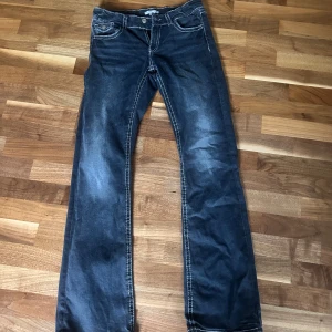 Mörkgråa lågmidjade jeans bootcut  - Mörkgåra jeans med vita sömmar. Väldigt lågmidjade och i bootcut 