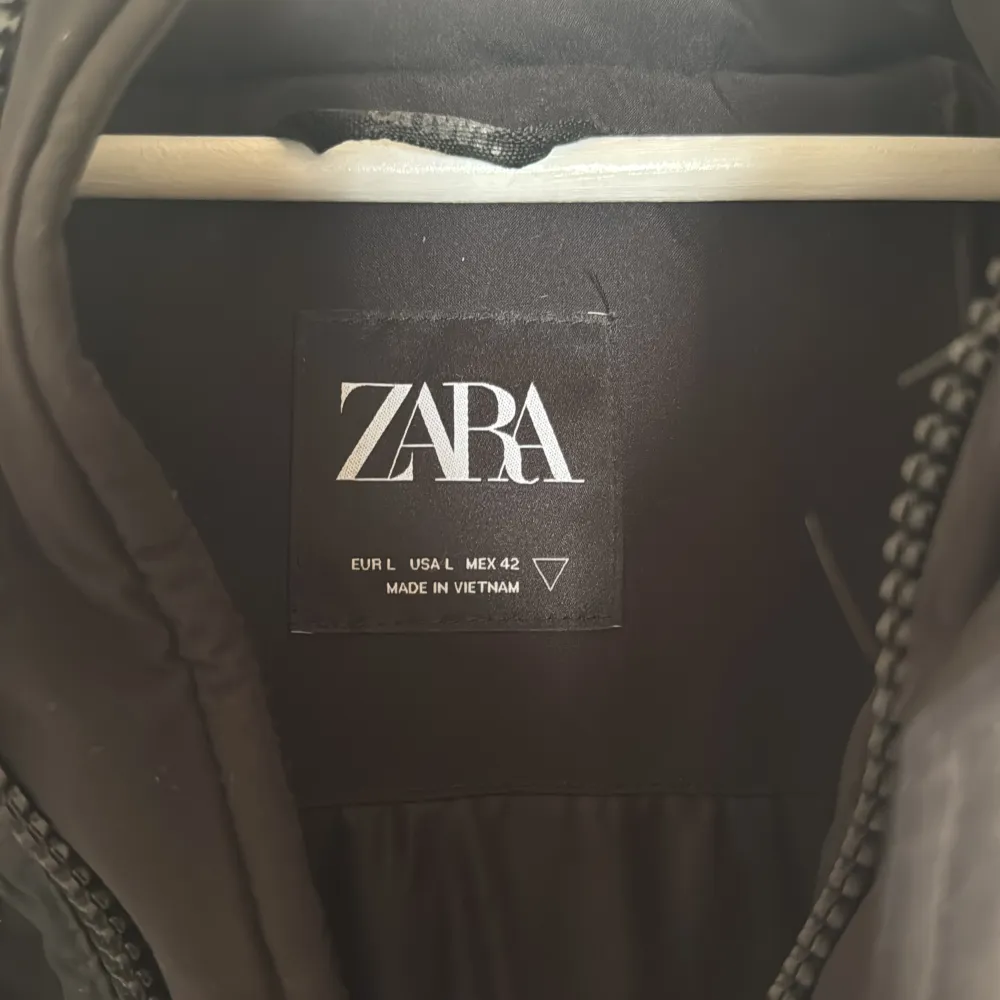 Säljer en svart dunväst från Zara med dragkedja och huva. Västen har en stilren design med två praktiska fickor framtill. Perfekt för kyligare dagar.. Takit.
