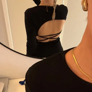 Svart klänning med öppen rygg - Snygg svart klänning med långärmad design och en iögonfallande öppen rygg med snörningsdetaljer. Perfekt för en kväll ute🌷