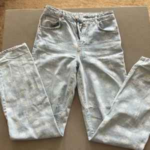 Ljusblå jeans med blommönster från Bik Bok - Säljer ett par ljusblå 90s straight jeans från Bik Bok med ett subtilt blommönster. De har en klassisk femficksdesign och stängs med dragkedja och knapp. Perfekta för en avslappnad stil nu till sommaren. Säljer dem då de är lite för små och har helt enkelt inte kommit till användning. Waist: 25 Length: 32