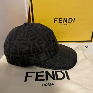 Keps från Fendi - Svart keps från Fendi. Perfekt för att ge din outfit en lyxig touch. Kepsen har en klassisk design med böjd skärm och justerbar passform.