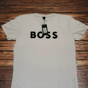 🔥💙Helt ny! Vit t-shirt från BOSS med tryck - Säljer en stilren vit t-shirt från BOSS med stor svart logotyp på bröstet. Klassisk passform och rund halsringning. Perfekt för dig som gillar enkla och snygga plagg med tydlig branding.