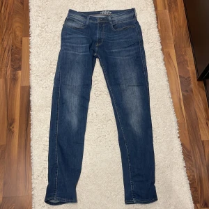 Blå jeansbyxor från Grant modell 521 - Säljer ett par klassiska blå jeansbyxor från Grant, modell 521. Byxorna har raka ben, fem fickor och lite mer åt tightare passformen. Tillverkade i slitstark denim med snygga ljusa tvättade partier på framsidan. Perfekta för dig som gillar tidlös stil.