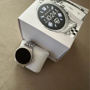Silverfärgad smartwatch från Michael Kors - Säljer en snygg och modern smartwatch från Michael Kors i silverfärgat rostfritt stål. Klockan har en rund urtavla med digital display och länkarmband. Perfekt accessoar för dig som vill ha både stil och smarta funktioner.