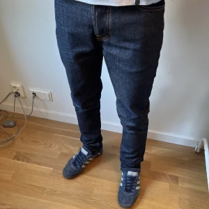 Mörkblå jeans från Nudie Jeans - Snygga mörkblå jeans från Nudie Jeans.     Modell: Grim Tim vilket är slim straight fit.      Storlek: W29 L32. Nypris för grim tim: 1600    Väldigt bra skick förutom en liten defekt på botten av jeansen som inte syns när man har på sig dem (se bild 4)