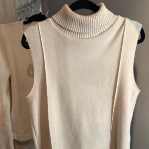 Beige stickad tröja med polokrage från Zara - Säljer en beige stickad tröja från Zara med hög ribbad polokrage. Tröjan är ärmlös och har en mjuk, stilren desifn. 