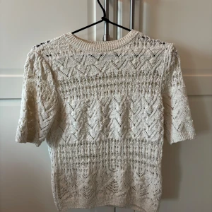 Vit spetsstickad topp från Zara - Säljer en vit, spetsstickad topp från Zara med korta ärmar och rund halsringning. Tröjan har ett vackert hålmönster och är perfekt för vår och sommar. Superfin att styla till både jeans och kjol!