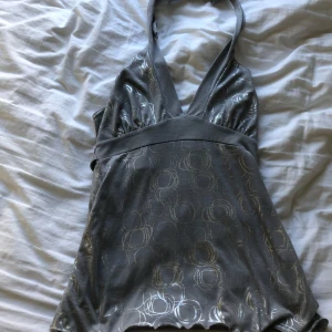 Silvergrå halterneck topp med mönster - Säljer en snygg silvergrå halterneck topp med glansigt cirkelmönster. Toppen har djup v-ringning och bred midjeresår som ger en fin passform. 