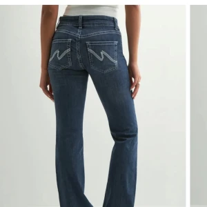 Blå bootcut jeans med vit broderad bakficka - Säljer ett par klassiska blå bootcut jeans med snygga vita broderade detaljer på bakfickorna. Jeansen har normal passform och är tillverkade i ett mjukt denimtyg. Perfekta för dig som gillar en tidlös stil med lite extra detalj på fickorna. Skriv vid funderingar💕