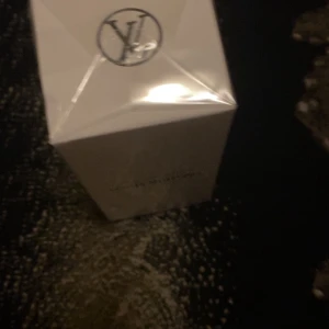 Imagination parfym från Louis Vuitton - Säljer en lyxig parfym från Louis Vuitton med namnet Imagination. Flaskan är elegant och genomskinlig med blå toner och svart kork. Förpackningen är vit med stilren design och Louis Vuitton-logga på toppen.
