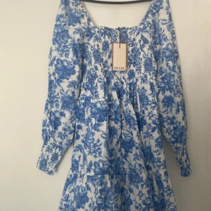 Blommig klänning från Vero Moda - Superfin vit och blå klänning från Vero Moda med blommigt mönster. Klänningen har långa ärmar, smock upptill och en luftig kjol. Perfekt till sommaren. Den är också helt ny med prislappen kvar. Pris kan diskuteras vid snabb affär. Tryck köp nu :)