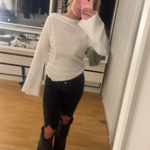 Vit ribbad långärmad tröja - Säljer en vit ribbad tröja med långa ärmar och lätt utsvängda ärmslut. Tröjan har en enkel och stilren design, perfekt att matcha med jeans eller kjol. Mjuk och bekväm att bära.