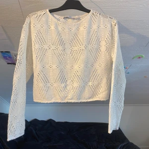 Vit virkad långärmad tröja från 157 - Säljer en vit virkad långärmad tröja från 157. Tröjan har ett genombrutet mönster och rund halsringning. Perfekt att styla över ett linne eller bikini för en trendig look.