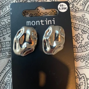 Silvriga statement-örhängen från Montini - Säljer ett par coola silvriga örhängen från Montini med organisk, skulptural form. Perfekta för dig som vill sticka ut med ett unikt accessoarval. Säljs i originalförpackning.