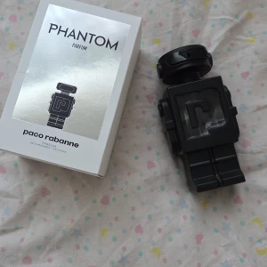 Phantom Parfum 150 ml från Paco Rabanne - Phantom Parfum från Paco Rabanne i en unik svart robotformad flaska. Parfymen levereras i en stilren vit och silverfärgad kartong. Flaskan rymmer 150 ml och har en modern, futuristisk design som sticker ut i parfymhyllan.