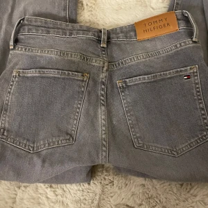 low waits botcut jeans - low waist grå jeans från Tommy Hilfiger med fem fickor och logga på bakfickan samt läderpatch i midjan. Jeansen är knappt använda💕