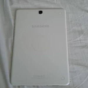 Samsung surfplatta vit - Säljer en vit Samsung surfplatta med stor skärm och kamera både fram och bak. Plattan har en stilren design med rundade hörn och tydliga knappar på framsidan. Perfekt för surf, appar och underhållning.