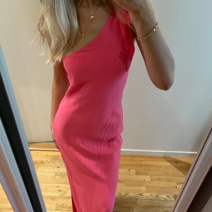 Rosa balklänning med oneshoulder - Säljer en elegant rosa långklänning med oneshoulder-design. Perfekt för speciella tillfällen med sin stilrena och moderna look. Klänningen har en smickrande passform och är tillverkad i ett mjukt material som faller fint. Litet tecken på användning längst ner på klänningen men inget som syns💕Lånade bilder