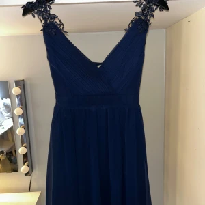 Marinblå klänning  - Marinblå kort klänning med fina spets detaljer på axelbanden. Oanvänd med lapp kvar