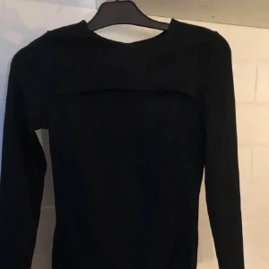 Klänning - Ribbad klänning med öppning vid brösten, den har aldrig kommit till användning. 