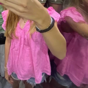 Rosa volangblus - Säljer en söt rosa blus med volangdetaljer på axlarna och vid ärmslut. Blusen har en lös passform och v-ringning med små rynkade detaljer framtill. Perfekt för vår och sommar! Storlek 170 men passar xxs-s!