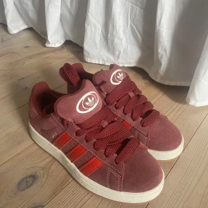 Adidas Campus sneakers i vinröd mocka - Säljer ett par Adidas Campus sneakers i vinröd mocka. Storlek 39 och en tredjedel. Perfekta till sommaren!!! Använda 1 gång. Skickar med både röda och vita snören. Öppen för prisförslag