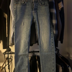 Blå raka jeans från Zara - Klassiska blå jeans från Zara med rak passform och femficksdesign. Jeansen har normal midja och subtila slitningar framtill. Perfekta till vardags för en avslappnad stil.
