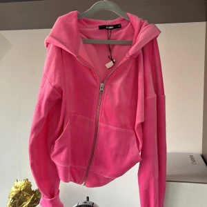 Rosa hoodie med dragkedja från Bik Bok - Säljer en mjuk och skön rosa hoodie från Bik Bok i storlek XS. Jackan har dragkedja framtill, huva och ribbade muddar. Perfekt för en avslappnad stil och enkel att matcha med jeans eller leggings.