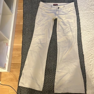 Beiga bootcut-byxor från Harvard USA - Säljer ett par beiga bootcut-byxor från Harvard USA med två knappar i midjan och klassiska fickor fram. Byxorna har en snygg, lite utsvängd passform och är perfekta för dig som gillar en stilren look. Använt de 3 gånger:))