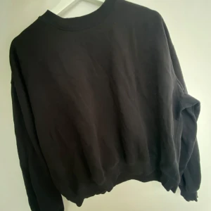 Svart sweatshirt från weekday - En enkel svart sweatshirt från weekday med rund hals och långa ärmar. Tröjan har en klassisk passform och ribbade muddar vid ärmslut och nederkant. Perfekt basplagg för garderoben.