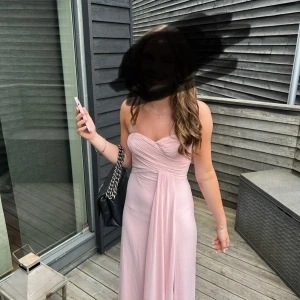 ljusrosa balklänning -  ljusrosa balklänning med draperad och lätt v-ringad överdel. Klänningen har en flowy kjol och är ärmlös, perfekt för bal!! Materialet är mjukt och faller snyggt längs kroppen. endast använd en gång och tvättad efter!!!  