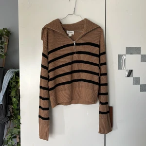 Beige och svart randig stickad tröja från Monki - Säljer en stickad tröja från Monki i beige med svarta ränder. Tröjan har halv dragkedja framtill, krage och långa ärmar. Perfekt för lager-på-lager och har en avslappnad passform.