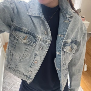 Ljusblå jeansjacka - Säljer en ljusblå jeansjacka med klassisk krage och knappar framtill. Jackan har två bröstfickor med lock och knapp samt tydliga sömdetaljer. Perfekt för vår och sommar, enkel att styla till olika outfits. Vet ej vad den är ifrån, om du vill ha bild på lappen så kan jag skicka privat