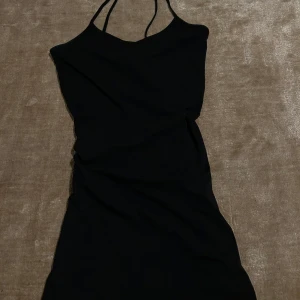 Svart klänning med smala band - Säljer en svart klänning med figurnära passform. Klänningen har en enkel och stilren design, perfekt för dig som gillar minimalistiskt mode. Materialet känns mjukt och följsamt mot kroppen.
