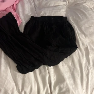 Svarta linnebyxor med resårmidja - Säljer ett par svarta linnebyxor i storlek S/M med resår i midjan. Byxorna är luftiga och har en avslappnad passform, perfekta för varma dagar eller en chill stil. Tillverkade i 100% linne och producerade i Italien.