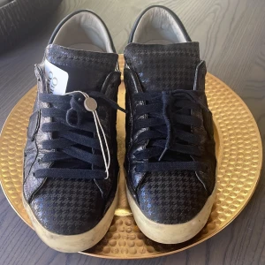 Svarta sneakers med mönster från Philippe Model - Säljer ett par svarta Philippe Model skor med inslag av silver och mönster på sulan som ger dem lite karaktär. De är använda med inga mer defekter än de man ser. De är äkthet och skick-kontrollerade av Vestiaire.                                     Hör av er vid frågor och pris kan diskuteras!