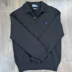 Ralph Lauren tröja med krage svart - En svart Ralph Lauren tröja med krage och lila inbroderat märke som är i väldigt bra skick och väl omskött! Märke • Ralph Lauren  Skick • 9/10 Storlek • S Modell • Tröja med krage Färg • Svart Frakt • skickas samma dag eller dagen efter köp Skriv gärna för mer information!