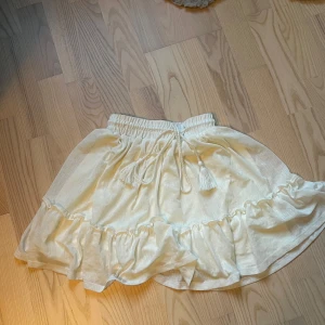 Vit volangkjol med knytband - Supersöt vit kjol med volangkant och knytband i midjan. Kjolen har resår i midjan🥰 Passar storlek xs och S